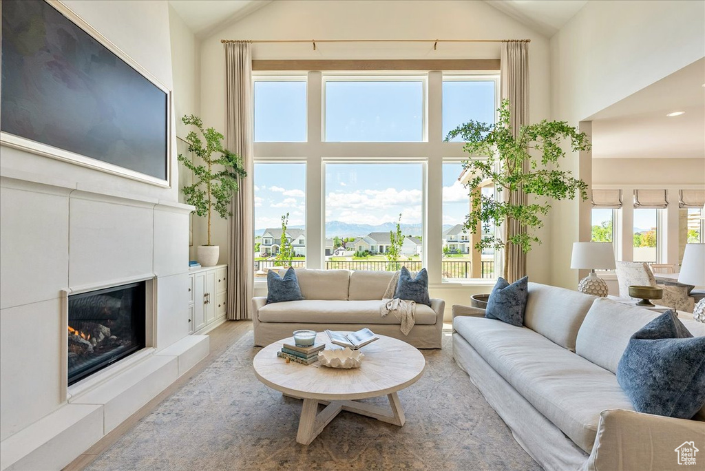 Living room featuring a tile fireplace, high vaulted ceiling, and wood finished floors