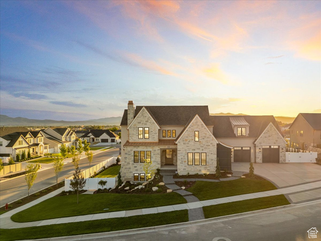 French country home with stone siding, concrete driveway, a residential view, and a chimney