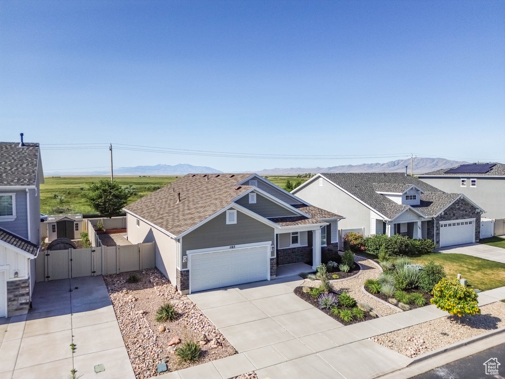View of front of property with a gate, concrete driveway, an attached garage, a mountain view, and stone siding