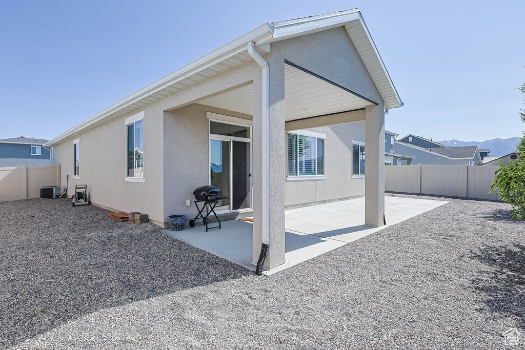 Rear view of house featuring stucco siding, cooling unit, and a patio