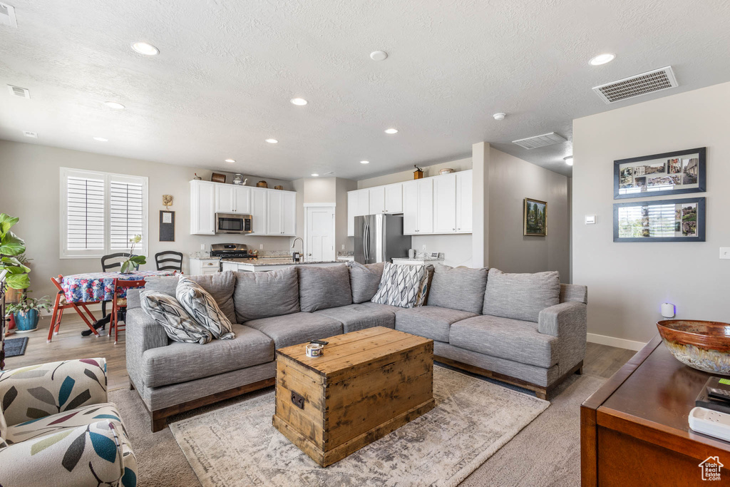 Living room featuring recessed lighting, a textured ceiling, and baseboards
