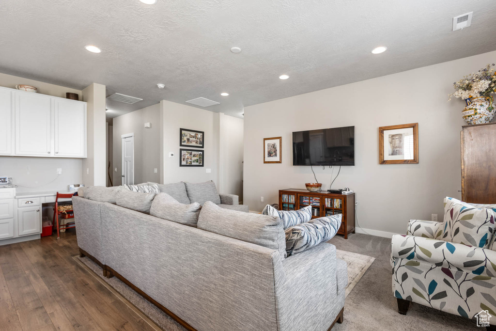 Living room with recessed lighting, baseboards, dark wood finished floors, and a textured ceiling