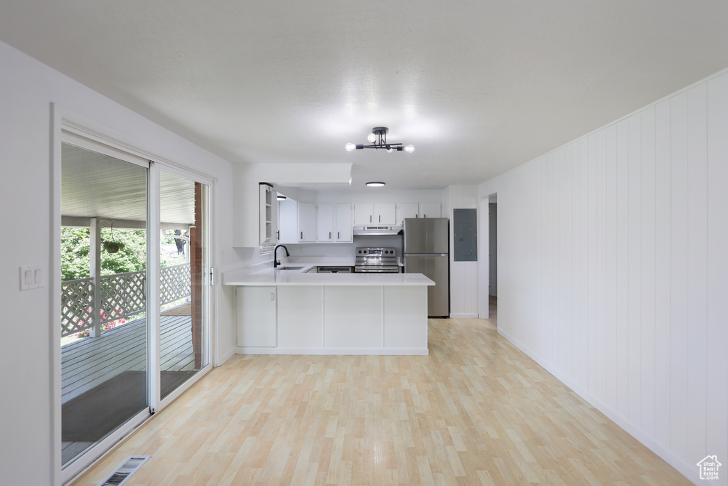 Kitchen with stainless steel appliances, light countertops, light wood finished floors, and a peninsula