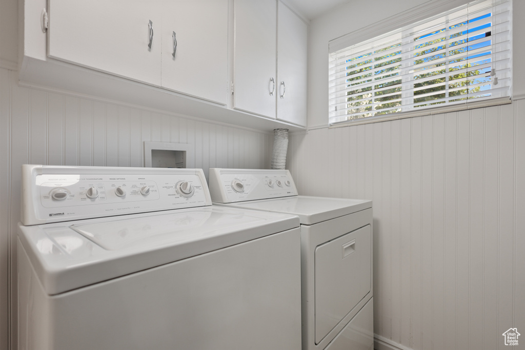 Laundry area with cabinet space, washing machine and dryer, and wooden walls