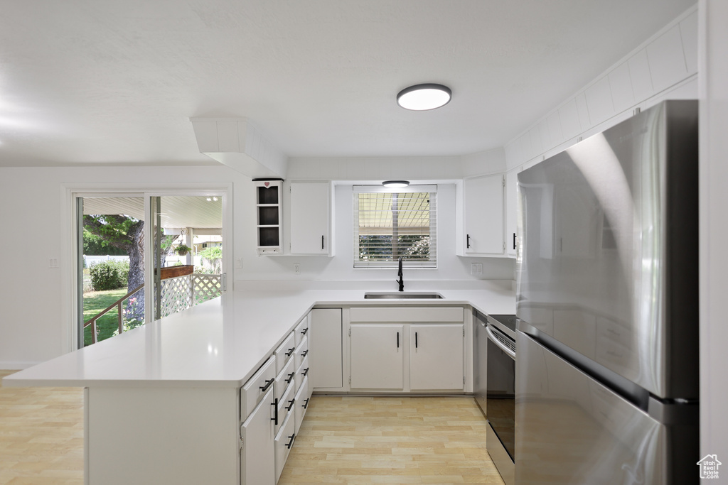 Kitchen with appliances with stainless steel finishes, a sink, plenty of natural light, and light countertops