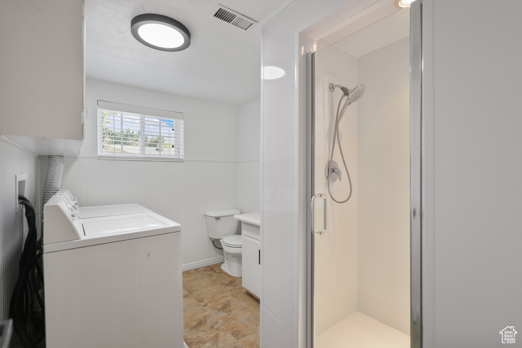 Full bath with a stall shower, toilet, vanity, and washing machine and clothes dryer