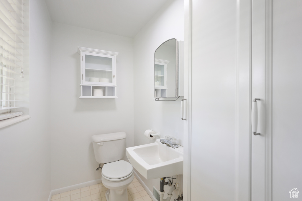 Half bath featuring a sink, toilet, and baseboards
