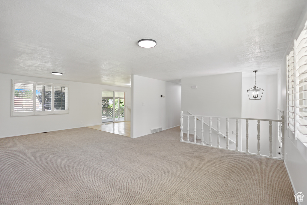 Carpeted spare room with a chandelier and a textured ceiling