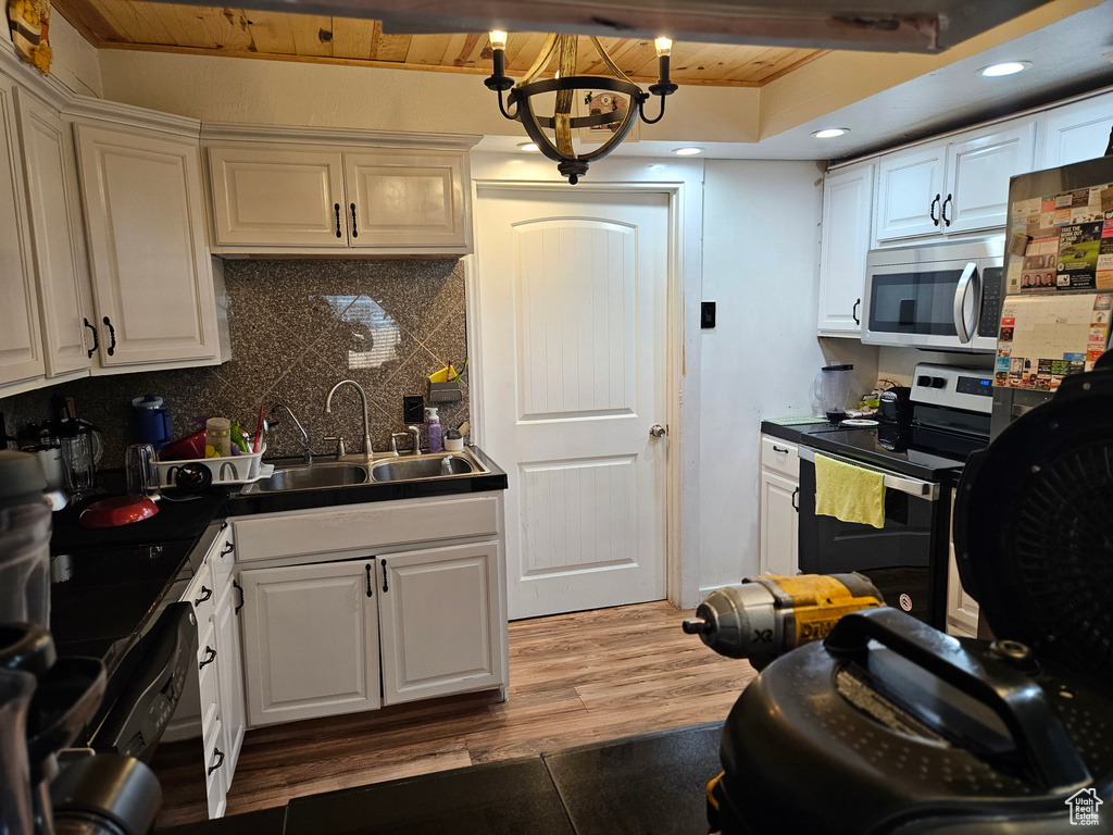Kitchen featuring stainless steel appliances, a sink, wood ceiling, tasteful backsplash, and white cabinetry
