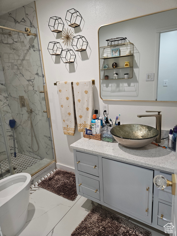 Bathroom featuring marble finish floors, a marble finish shower, vanity, and baseboards