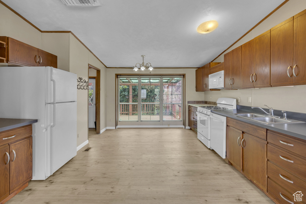 Kitchen with a sink, white appliances, brown cabinets, a chandelier, and crown molding