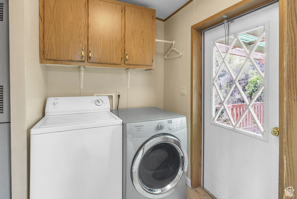 Washroom featuring washer and dryer, cabinet space, and plenty of natural light