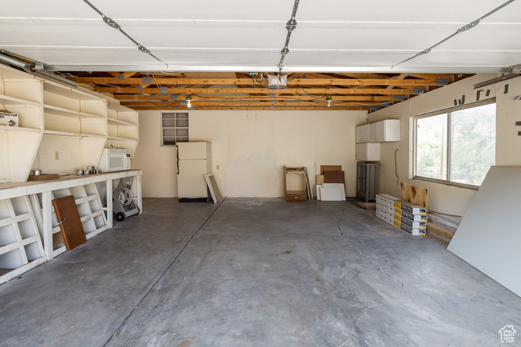 Garage featuring freestanding refrigerator and a garage door opener