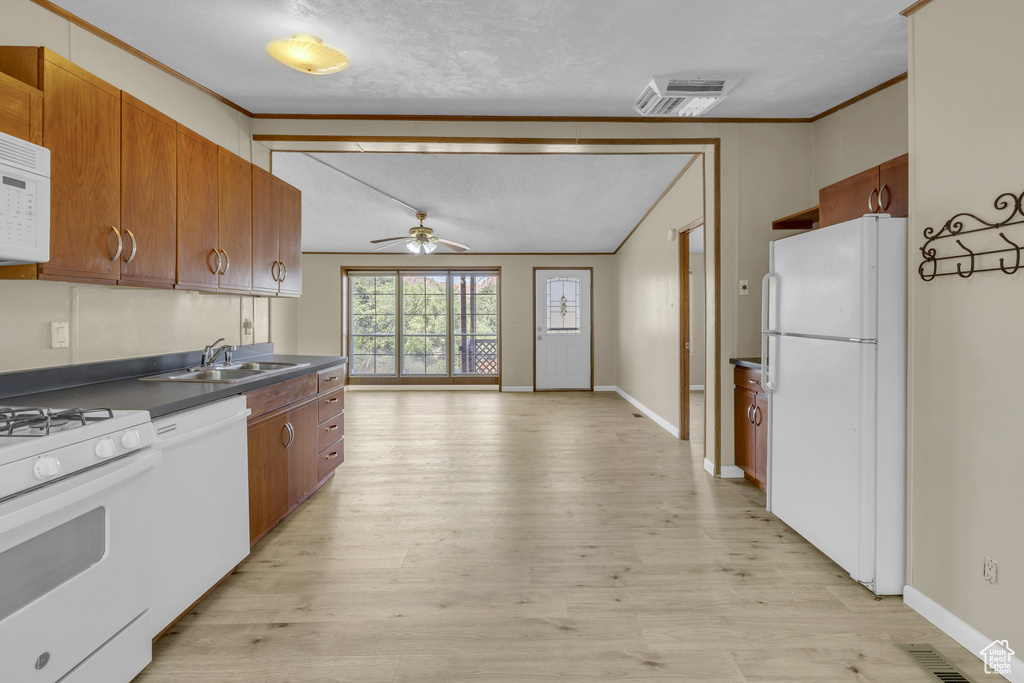 Kitchen with white appliances, ceiling fan, dark countertops, a sink, and crown molding