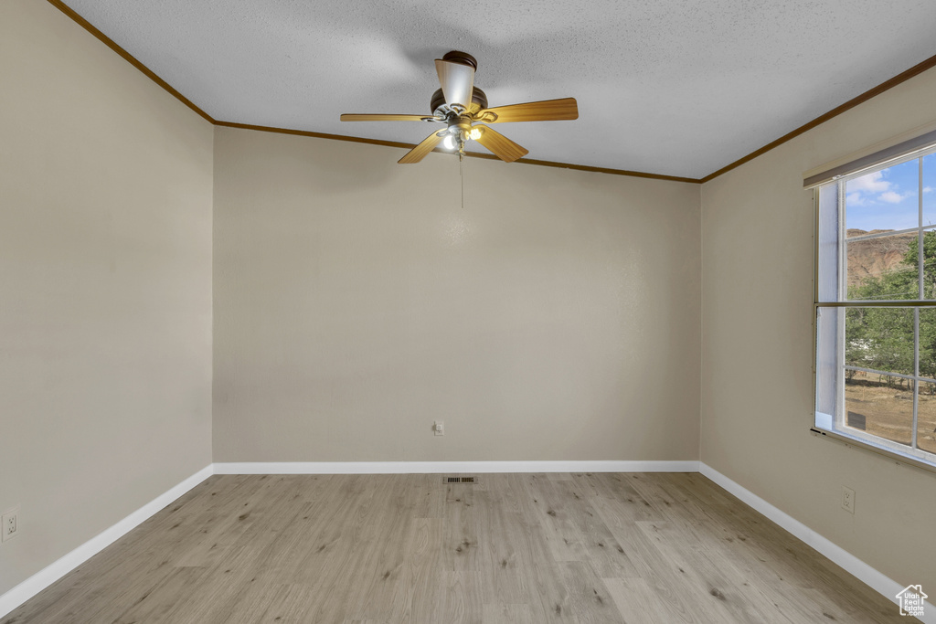 Unfurnished room with ornamental molding, wood finished floors, baseboards, and a ceiling fan