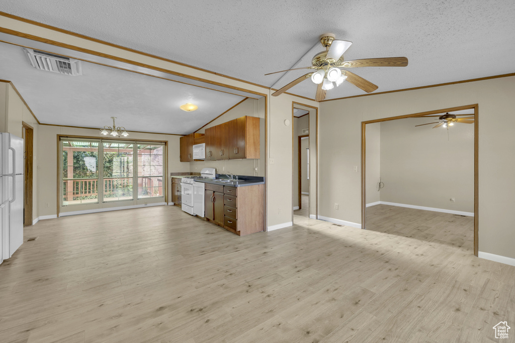 Kitchen with white appliances, open floor plan, a textured ceiling, a ceiling fan, and brown cabinets