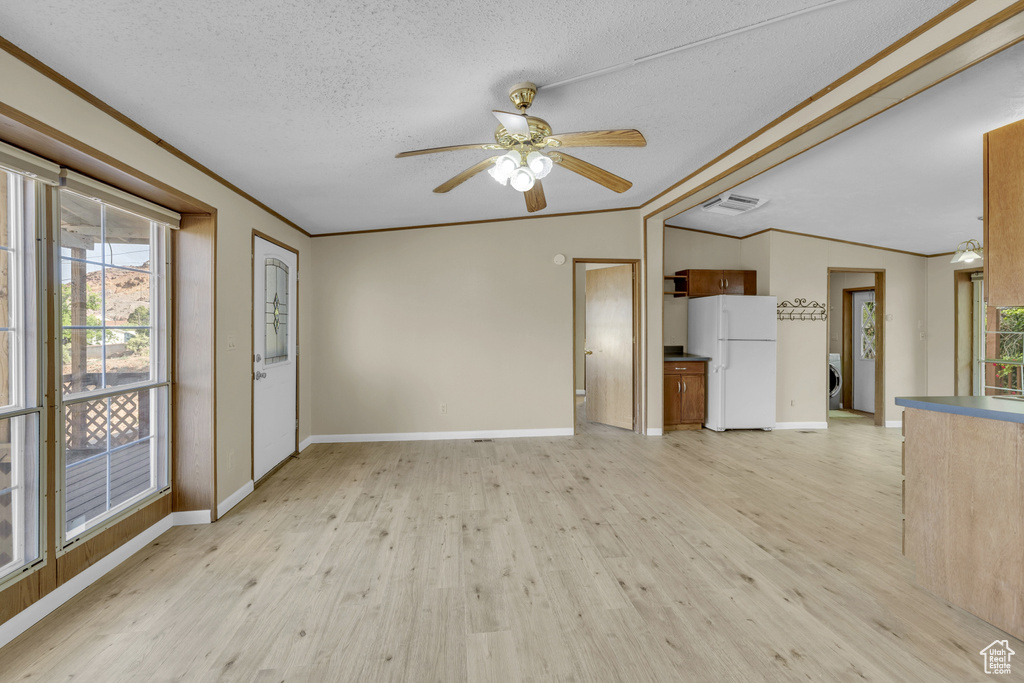 Unfurnished living room with ornamental molding, light wood finished floors, a ceiling fan, baseboards, and a textured ceiling