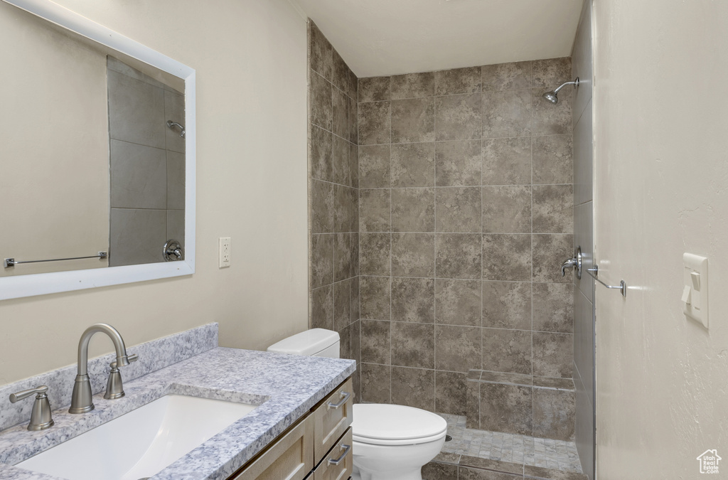 Bathroom featuring toilet, vanity, and tiled shower