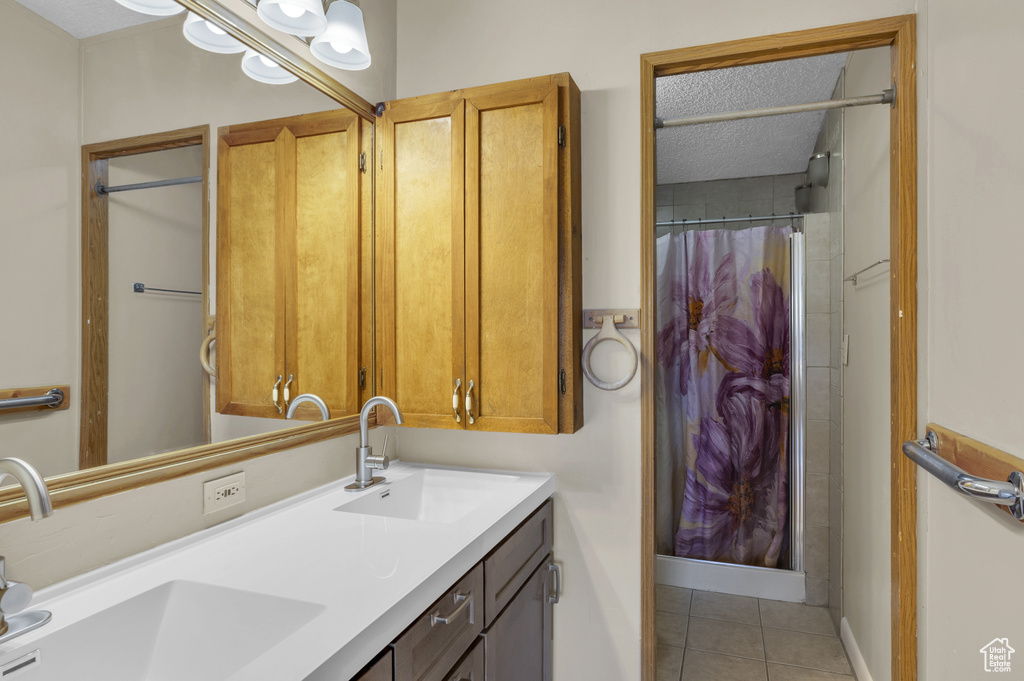 Full bathroom with double vanity, tile patterned flooring, a shower with shower curtain, and a textured ceiling