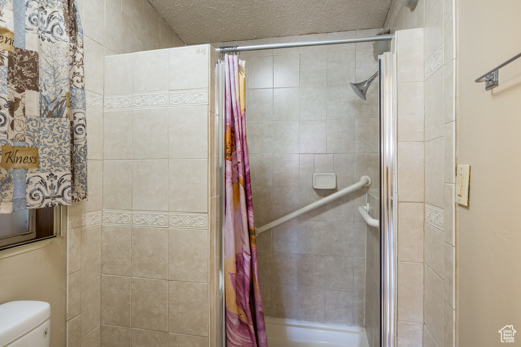 Full bath with a shower stall, toilet, and a textured ceiling