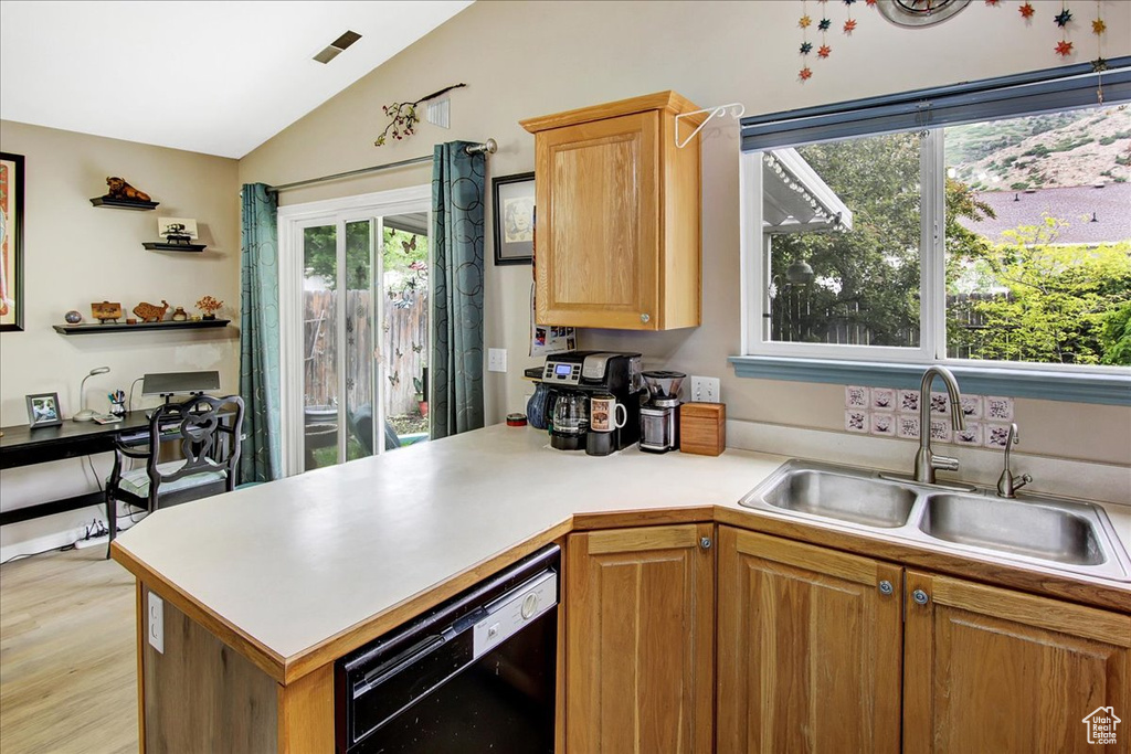 Kitchen with dishwasher, a sink, vaulted ceiling, a peninsula, and light countertops