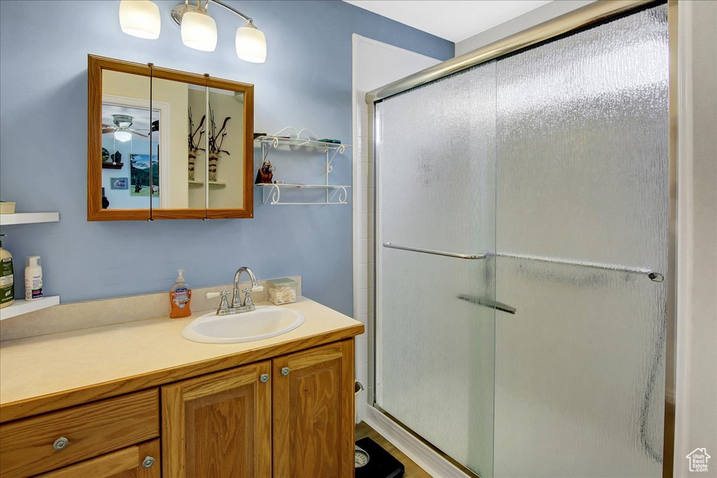 Full bath featuring vanity, a shower stall, and a ceiling fan