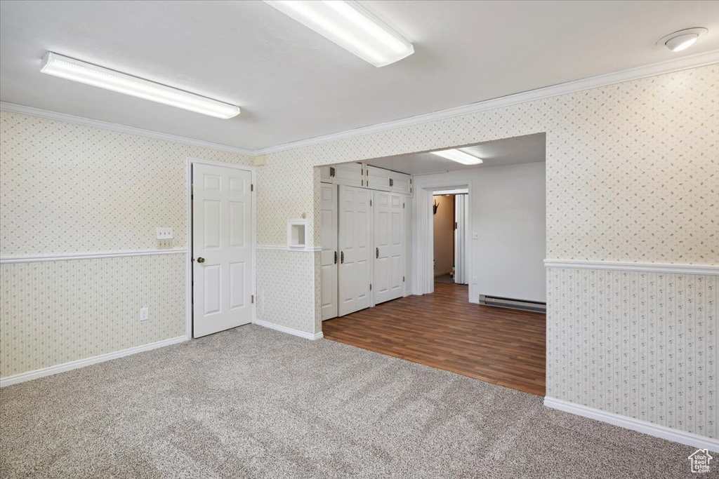 Spare room featuring ornamental molding, carpet, wallpapered walls, baseboards, and a baseboard heating unit
