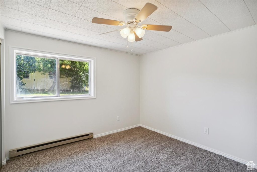 Empty room with a baseboard radiator, carpet floors, a ceiling fan, and baseboards
