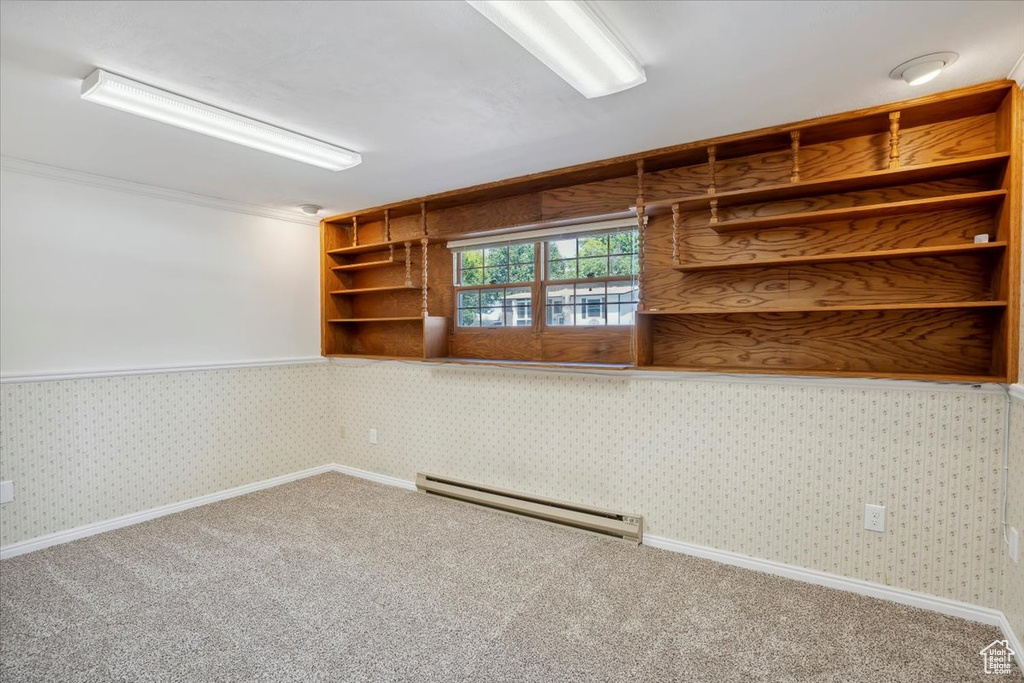 Carpeted spare room featuring a baseboard radiator, wallpapered walls, and baseboards