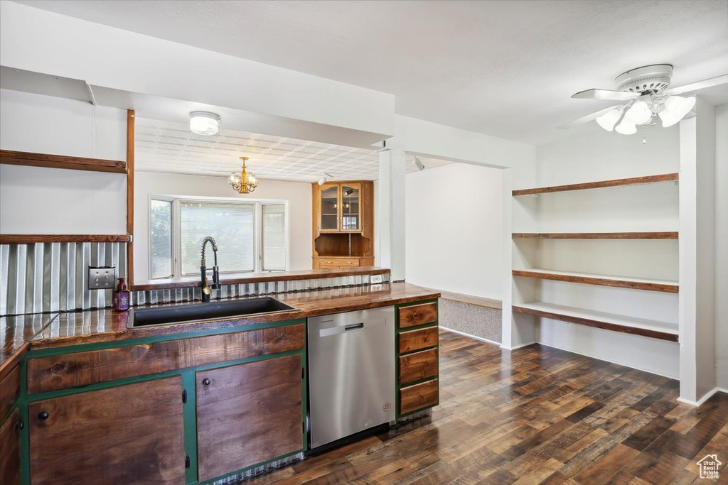 Kitchen with dishwasher, a sink, dark countertops, and dark wood-style floors