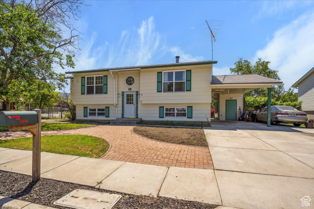 Raised ranch with concrete driveway and an attached carport