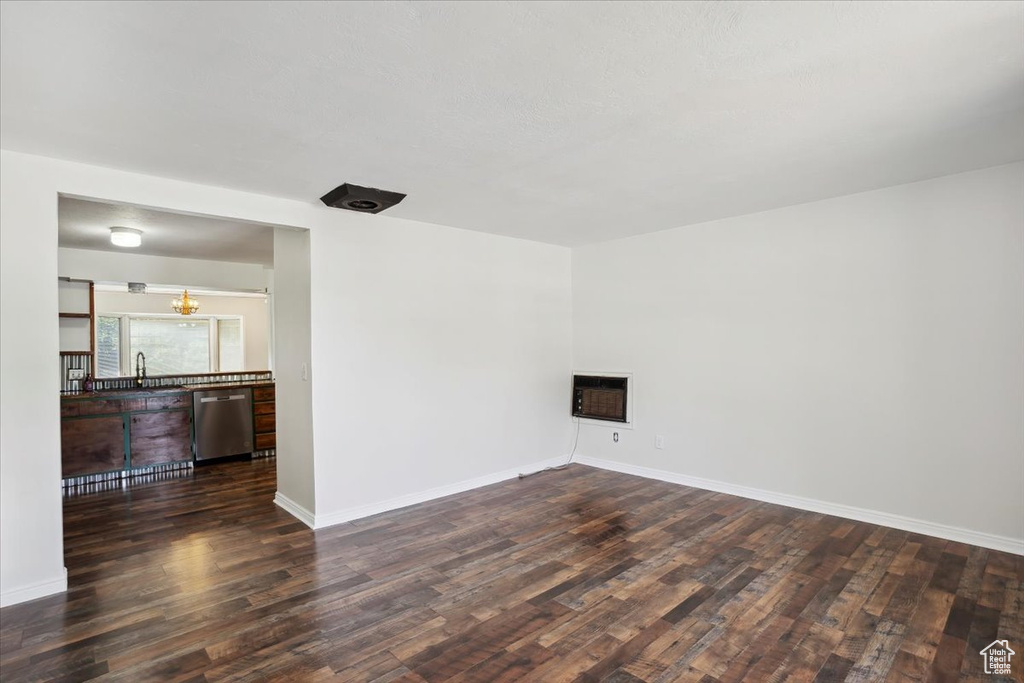Unfurnished room featuring dark wood-style floors, a sink, heating unit, and baseboards