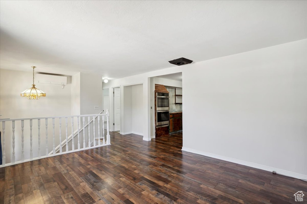 Empty room with wood finished floors, a wall mounted AC, and baseboards
