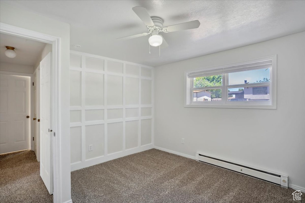 Spare room with a baseboard heating unit, carpet, ceiling fan, and baseboards