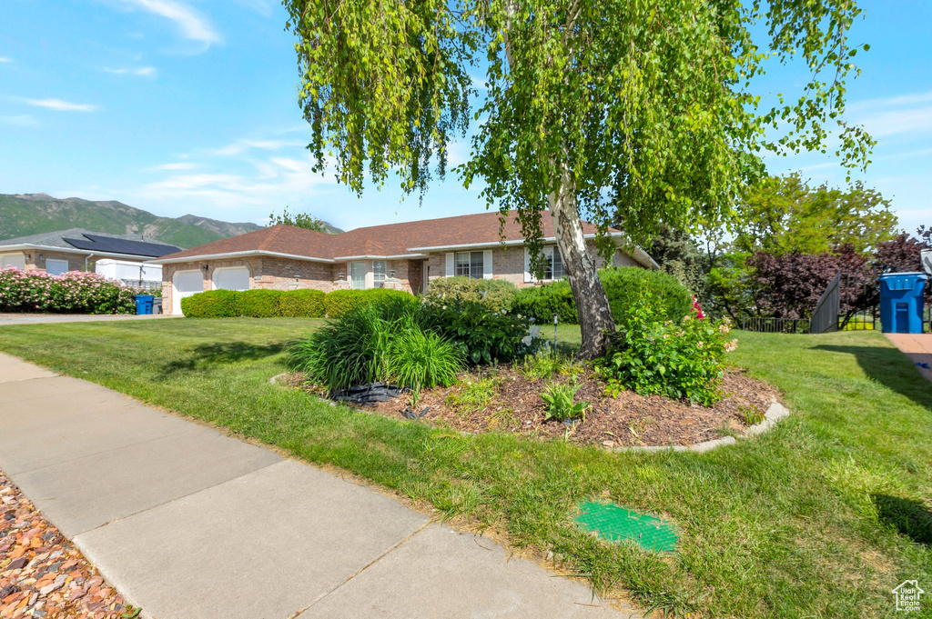 Ranch-style home featuring a garage, a front yard, a mountain view, and driveway