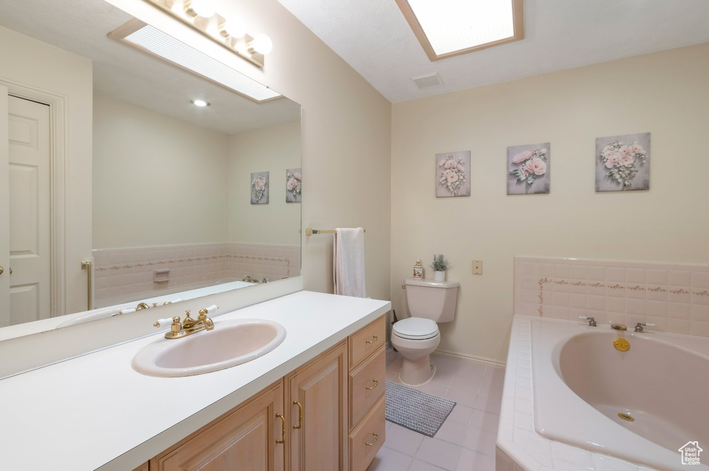 Full bathroom featuring tile patterned flooring, a bath, vanity, toilet, and baseboards