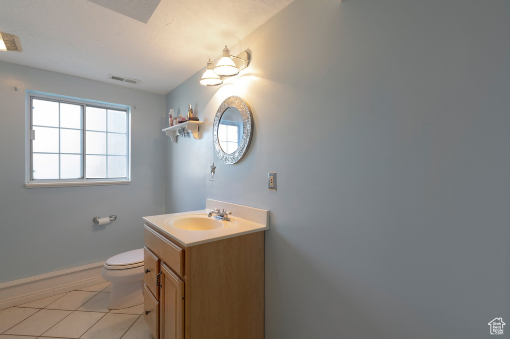 Bathroom featuring toilet, vanity, baseboards, and tile patterned flooring
