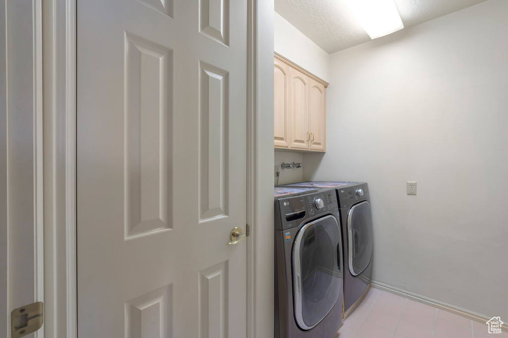 Laundry area featuring washing machine and clothes dryer, cabinet space, and light tile patterned floors
