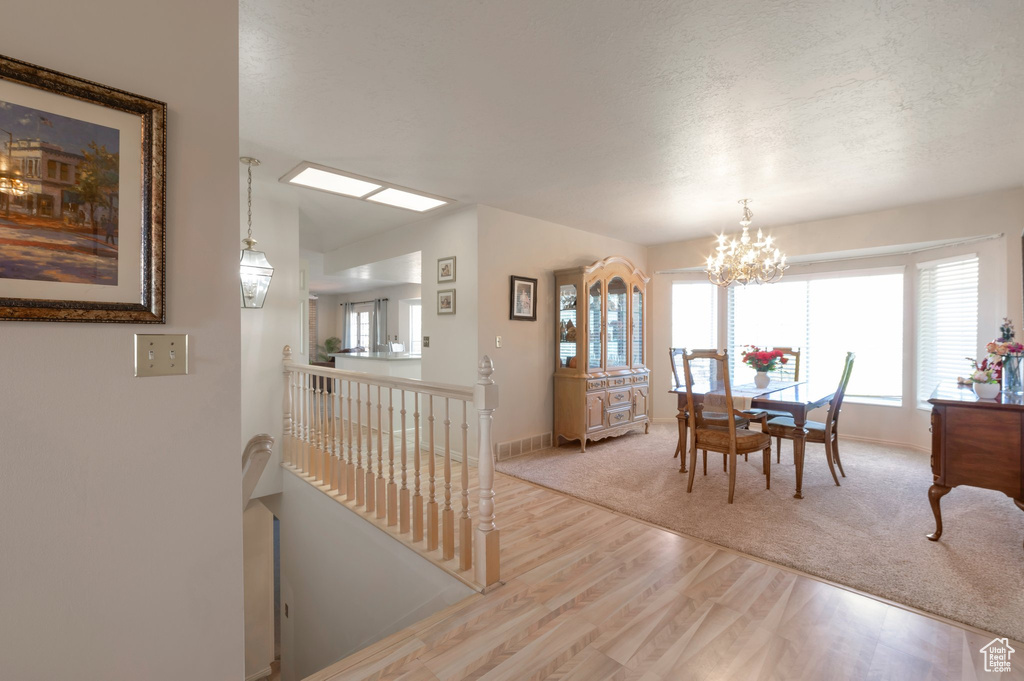 Dining room featuring wood finished floors, a chandelier, baseboards, and a textured ceiling