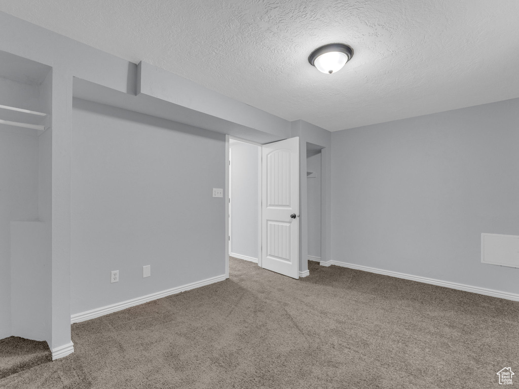 Basement with carpet flooring, a textured ceiling, and baseboards