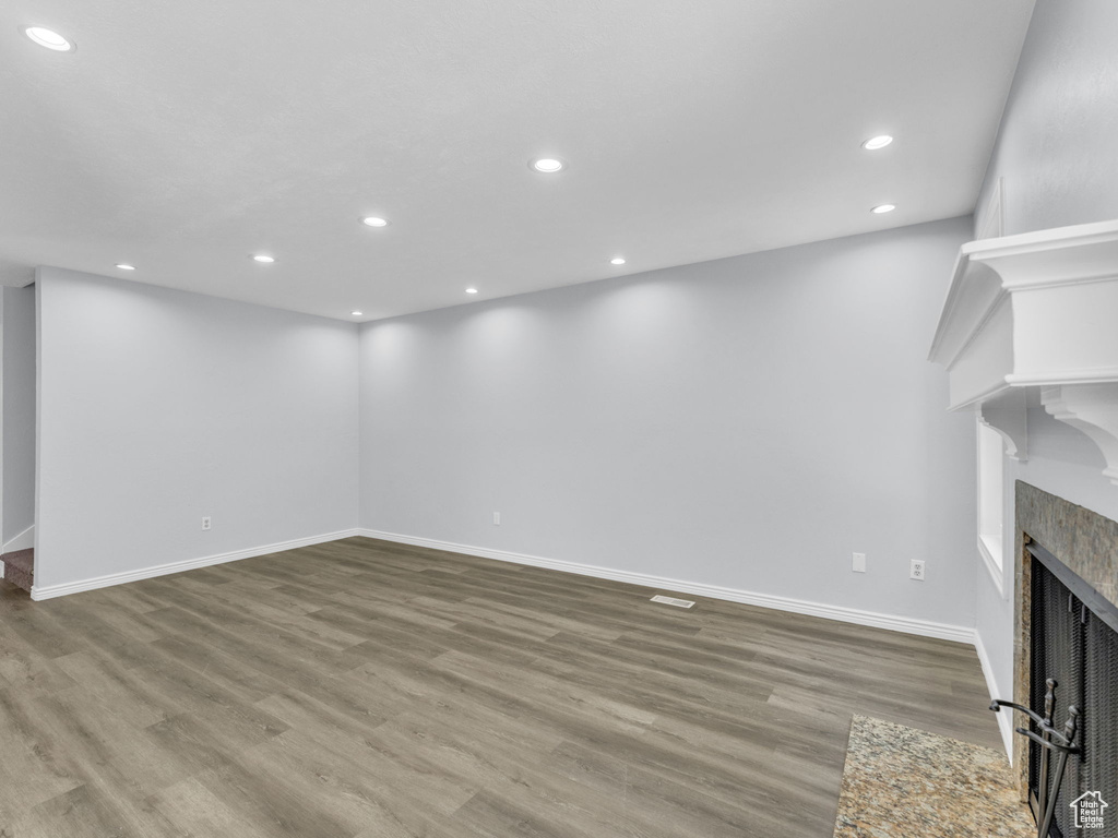 Unfurnished living room with wood finished floors, recessed lighting, baseboards, and a fireplace with flush hearth