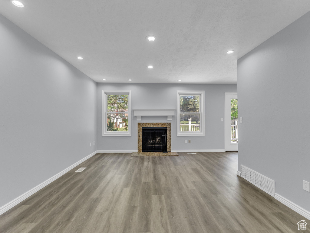 Unfurnished living room featuring wood finished floors, recessed lighting, a premium fireplace, baseboards, and plenty of natural light