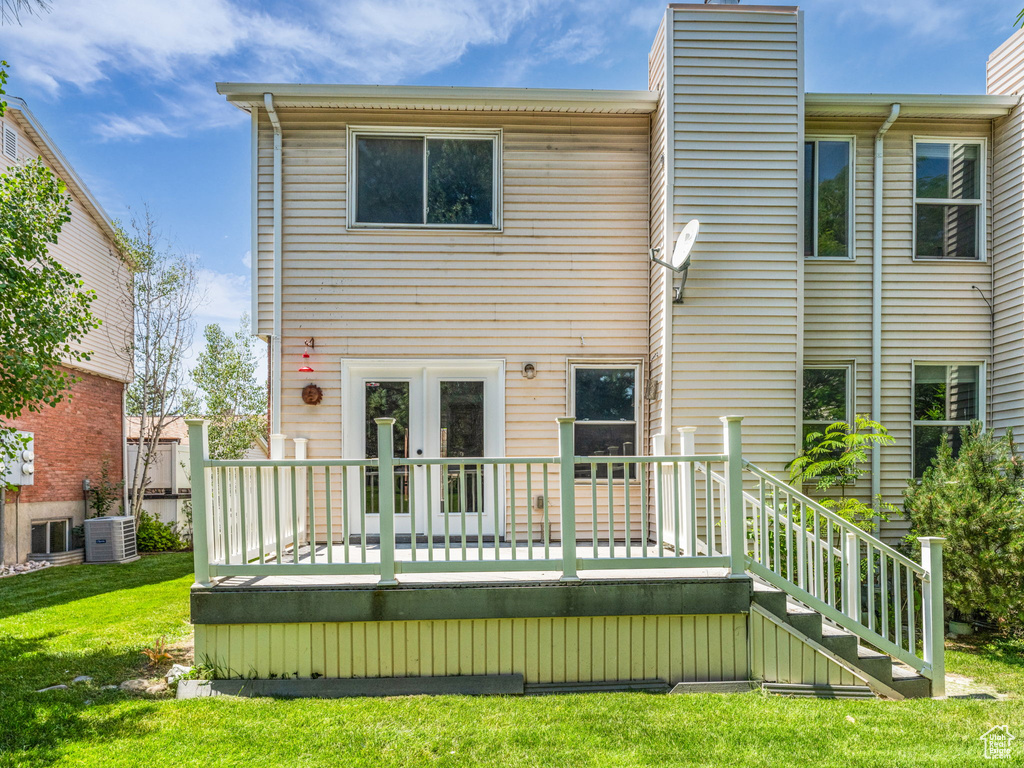 Back of property with a chimney, central AC unit, french doors, a wooden deck, and a yard