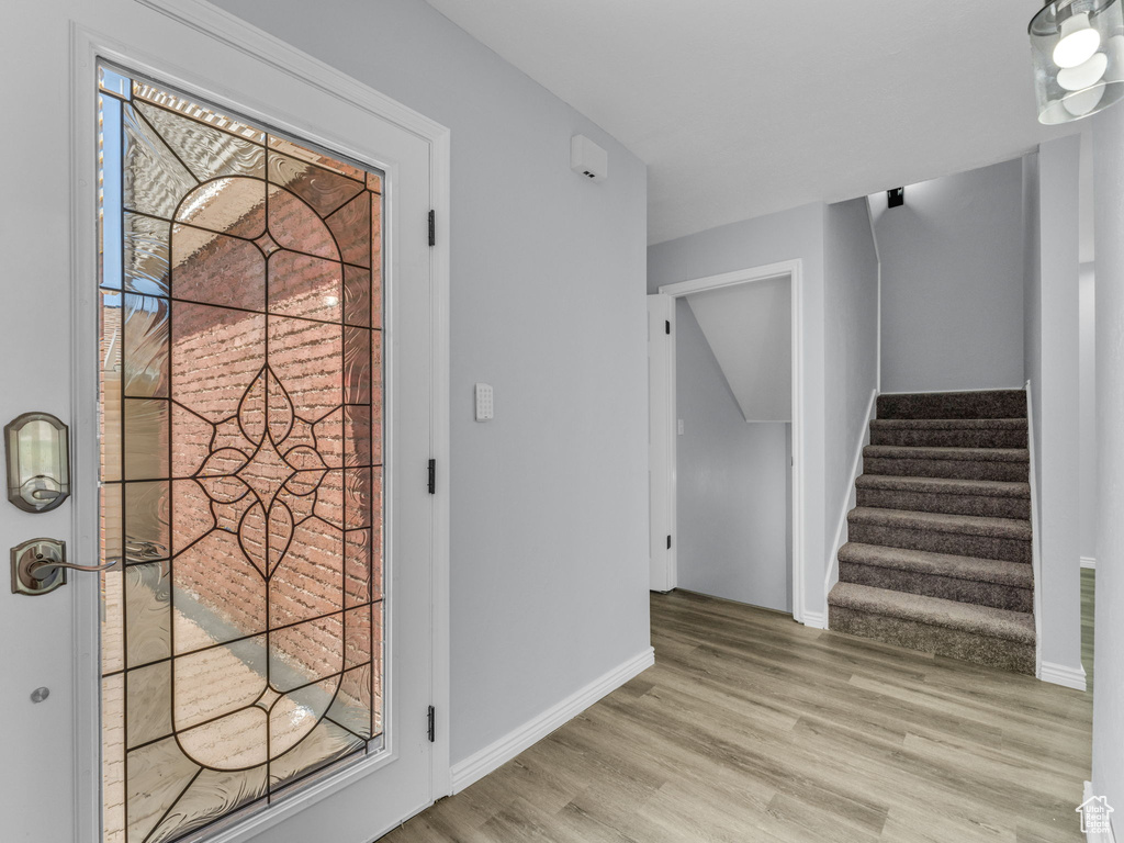 Entryway with light wood finished floors, stairway, and baseboards