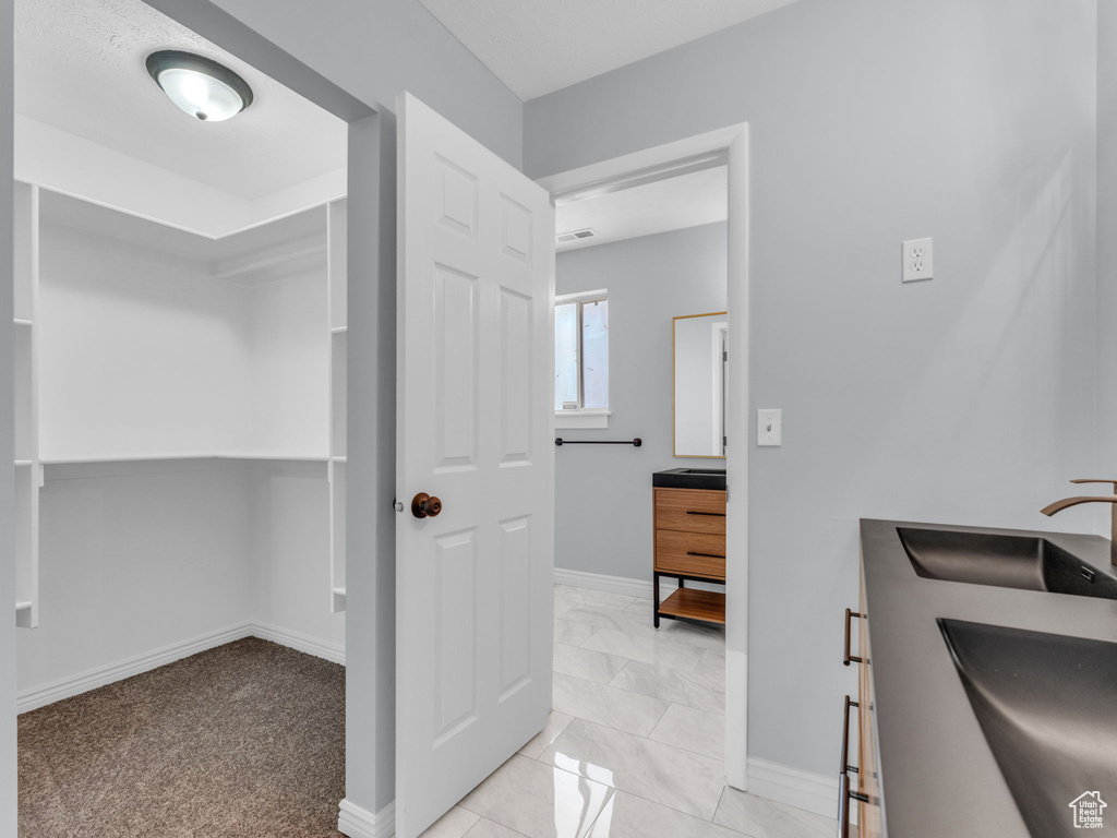 Bathroom featuring double vanity, baseboards, and marble look tiles