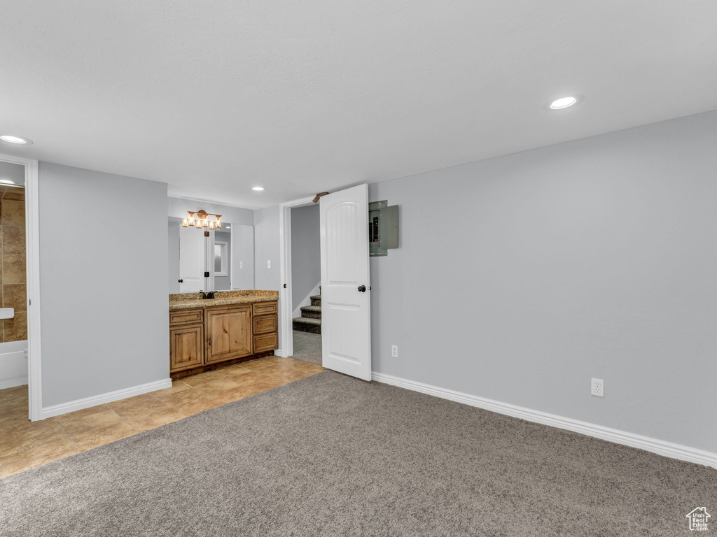 Unfurnished bedroom featuring recessed lighting, connected bathroom, baseboards, electric panel, and light tile patterned flooring