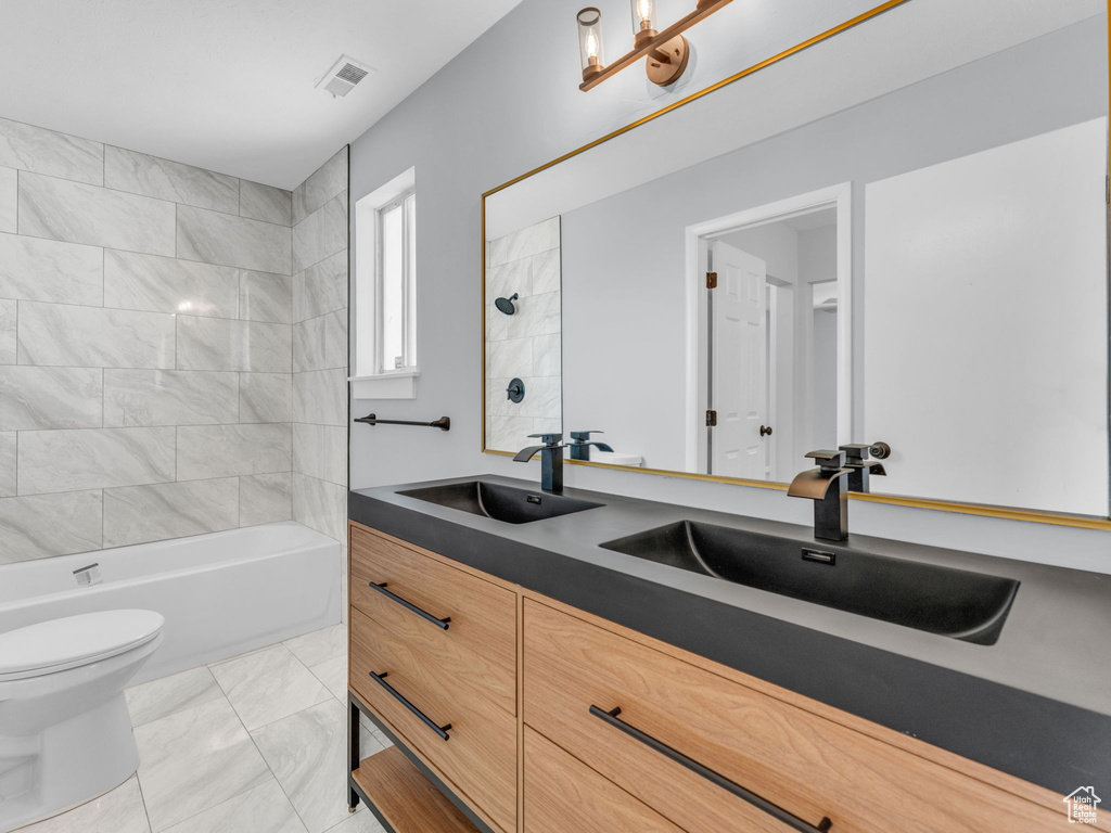 Full bath featuring toilet, double vanity, marble finish flooring, and bathtub / shower combination