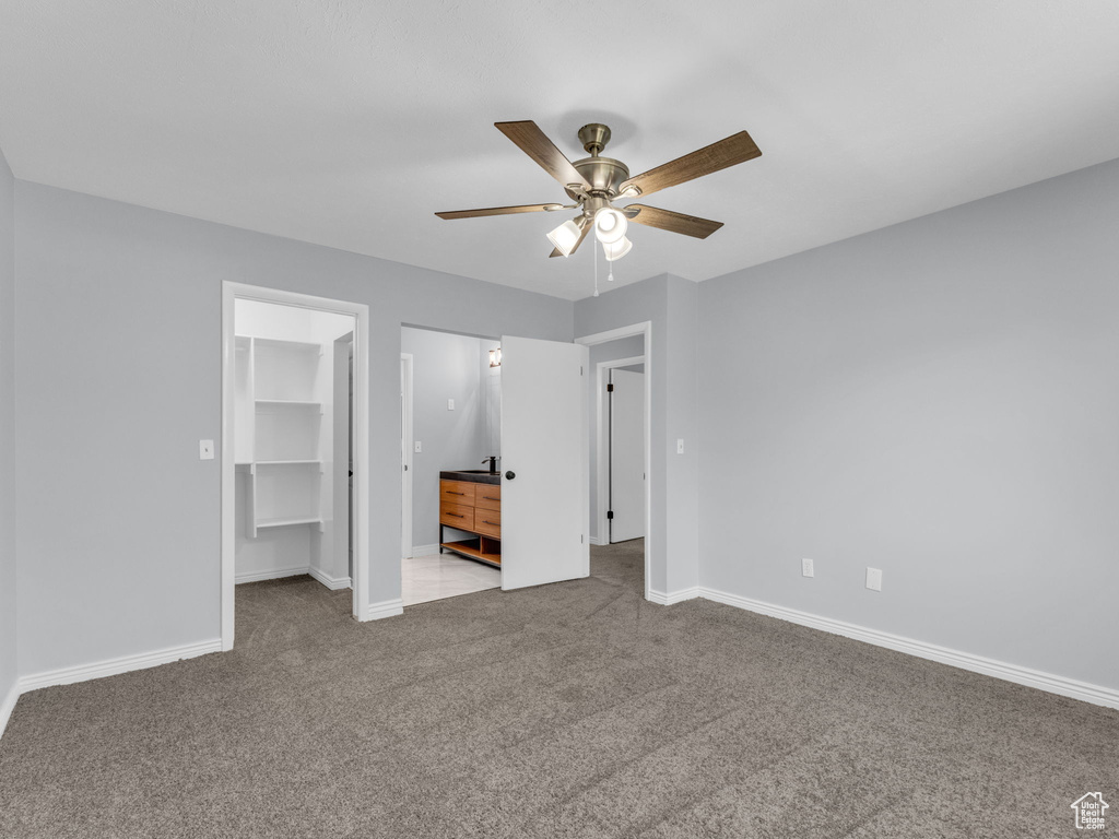 Unfurnished bedroom with a walk in closet, carpet flooring, baseboards, and a closet