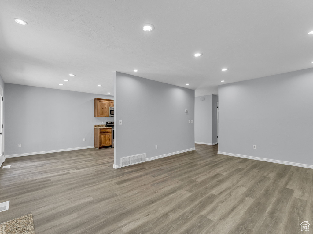 Unfurnished living room featuring recessed lighting, baseboards, and light wood-type flooring