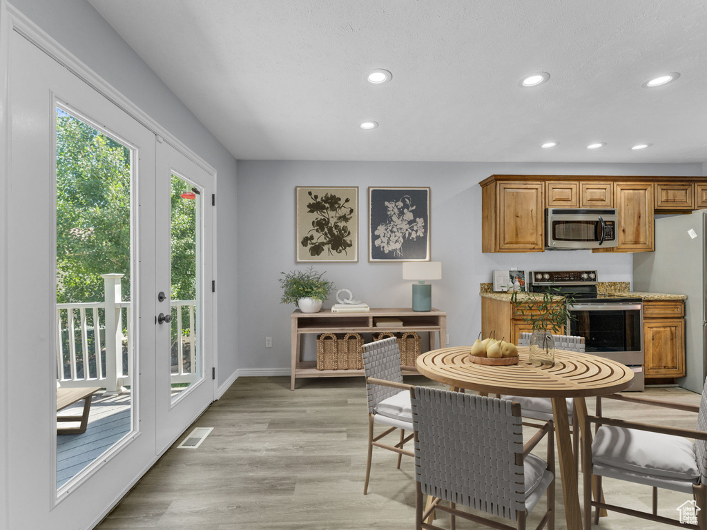 Kitchen with stainless steel appliances, recessed lighting, light wood-style floors, brown cabinets, and baseboards